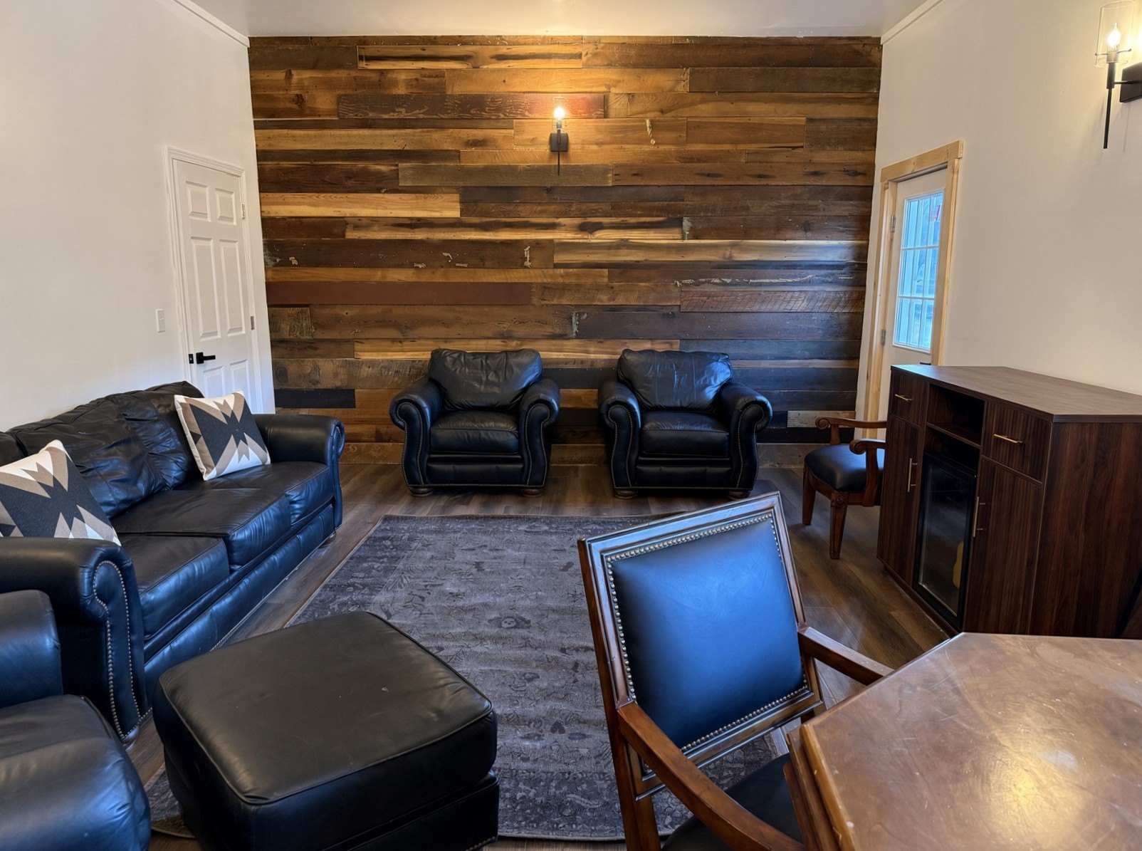 Groom suite with leather sofas, armchairs, and a wood accent wall