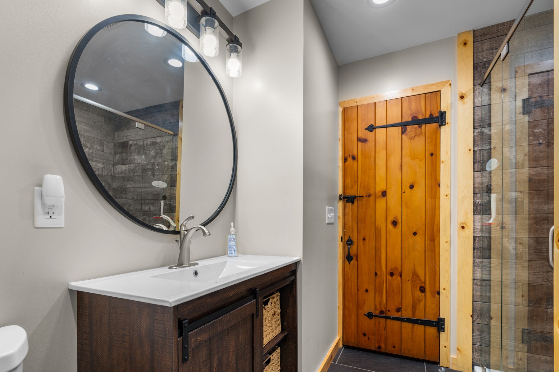 Lodge bathroom with a round mirror and glass shower