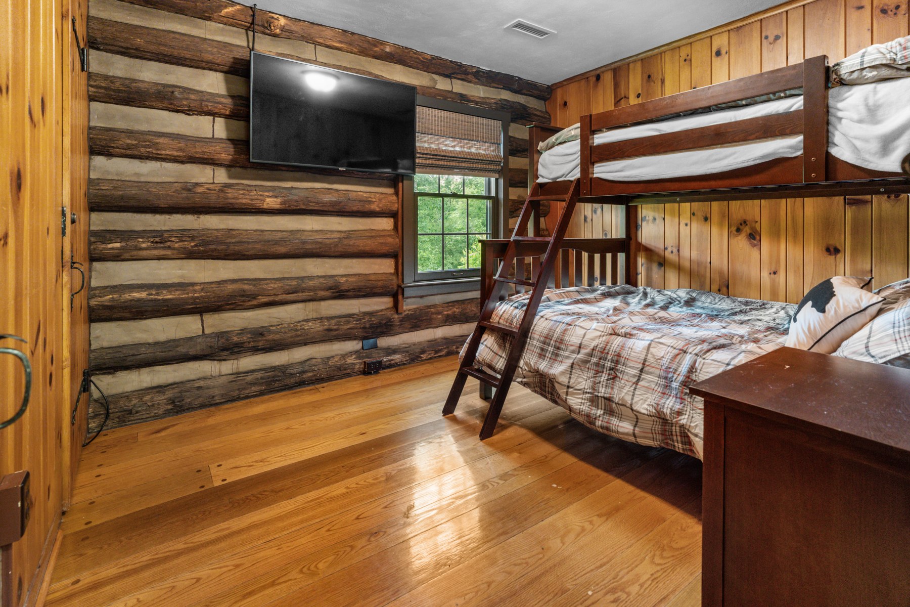 Lodge bunk bedroom with wooden walls and a view of the grounds