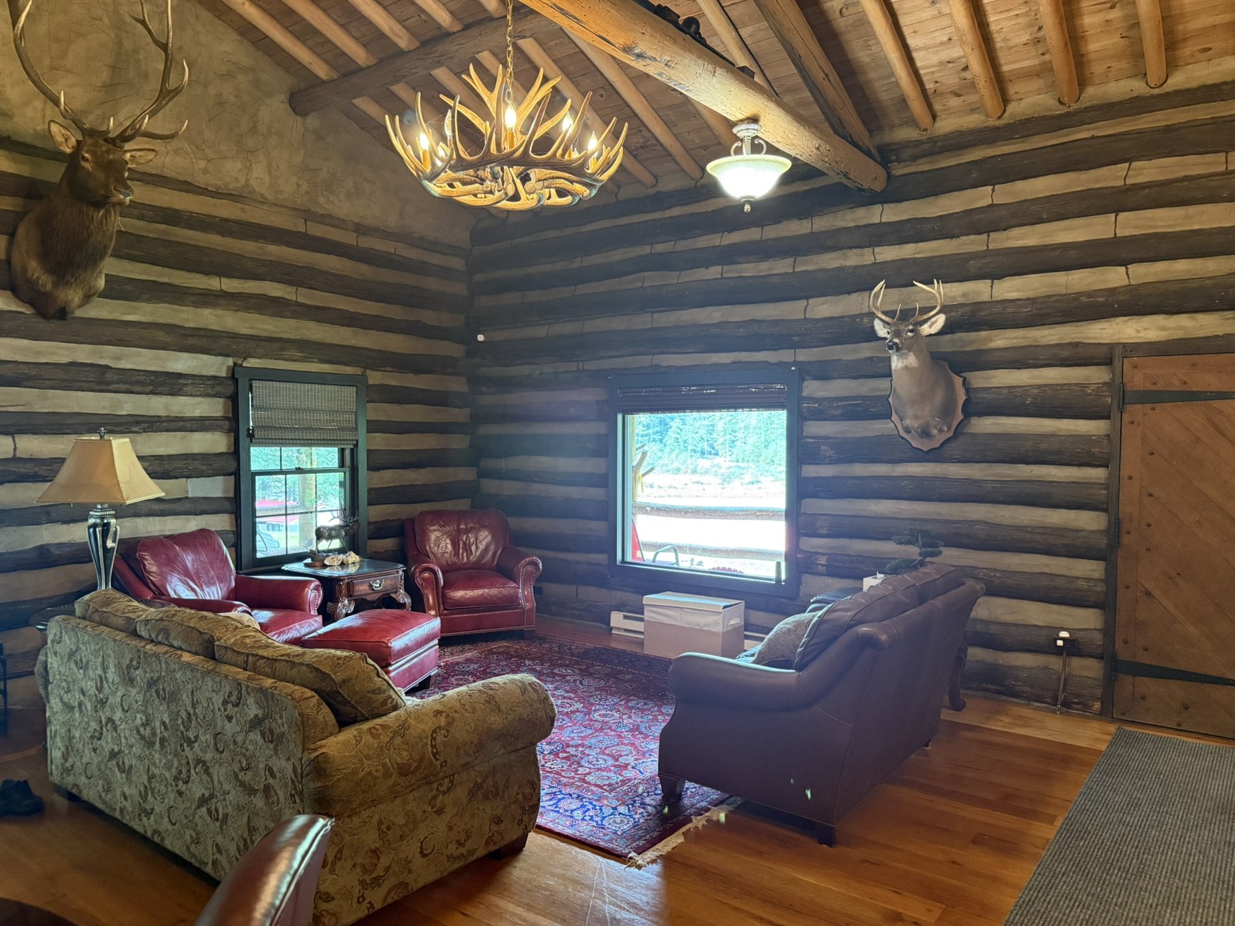 Lodge sitting room with timber walls, exposed beams, and seating by the window